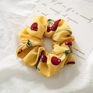 Detailed close-up of yellow scrunchie with red cherry pattern on soft fabric