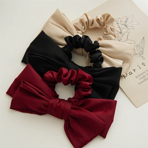Close-up of matte satin double-layered bow scrunchies in beige, black and burgundy