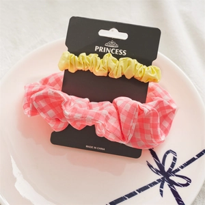 Detail of 2-piece hair scrunchie set in yellow and pink plaid on a ceramic display plate
