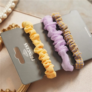 Detailed view of chiffon scrunchies set in yellow, lavender and plaid on card