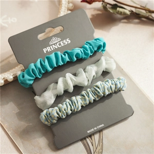 Detailed view of three assorted aesthetic scrunchies on a grey display card with floral decor
