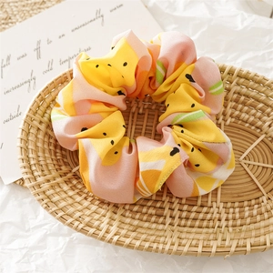 Close-up of pink and yellow watermelon print fabric scrunchie on a soft cream background