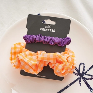 Detail of 2-piece hair scrunchie set in purple and orange plaid on black card packaging
