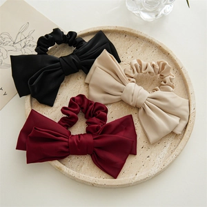 Close-up of elegant satin double-layer bow scrunchies in black, beige, and burgundy colors