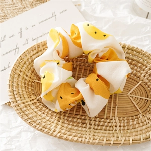 Close-up of yellow fruit print fabric scrunchie in a woven basket for hair styling