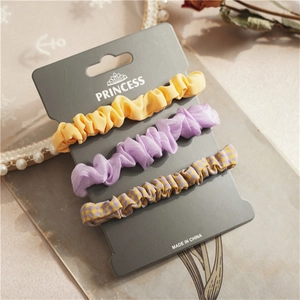 Detailed view of three-piece set floral and solid hair scrunchies on a premium display card