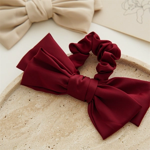 Close-up detail of double-layered satin bow hair scrunchie in deep wine red color