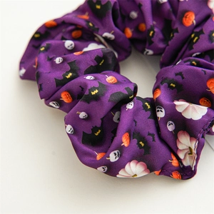 Vue macro d'un chouchou en satin violet avec motifs de citrouilles et de chauves-souris