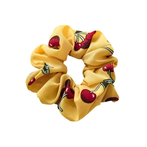 Yellow scrunchie with red cherry print made of lightweight fabric for women hair styling