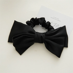Detail of elegant black double-layered satin bow hair tie with smooth silk texture