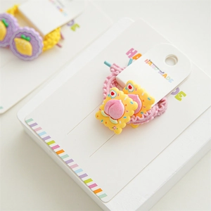 Close-up of handmade kids hair ties with resin fruit charms on card packaging