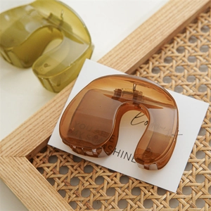 Close-up of amber and olive green resin hair claws on a rustic wooden display stand