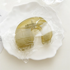 Detail view of a translucent olive green acrylic hair claw clip with a sturdy metal spring