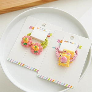 Detail of peach cookie and flower hair ties on a handmade card in a white tray