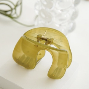Detail of olive green acrylic hair claw clip with golden spring on geometric tray