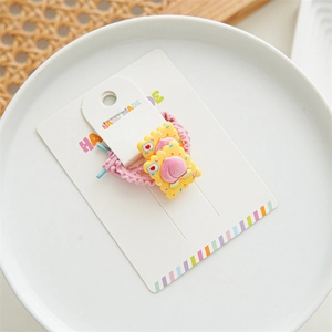 Detail of pink knitted hair tie with yellow biscuit resin charms on a display card