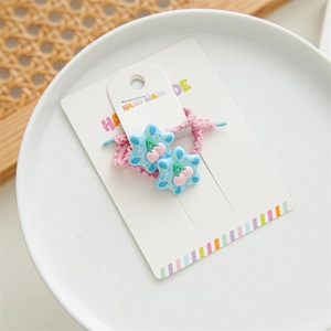 Close-up of pink elastic hair ties with star-shaped cherry charms on a display card