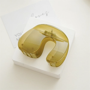 Macro shot of olive green translucent resin hair claw with golden spring mechanism