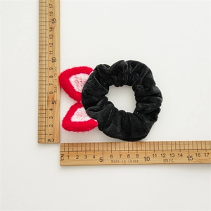 Détail d'un chouchou noir en peluche avec oreilles de chat et mesure de 8,5cm de diamètre