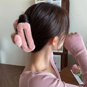 Dettaglio della molletta per capelli in finta pelliccia rosa indossata da modella