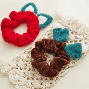 Détail des chouchous en peluche rouge et marron avec oreilles de chat sur fond tissé