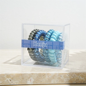 Close-up of assorted blue and grey spiral hair ties in a clear minimalist display box