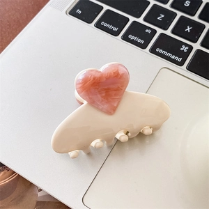 Detail einer Haarklammer aus Acetat mit rosa Herzanhänger auf einer Laptopfläche