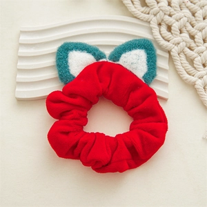 Détail d'un chouchou en peluche rouge avec des oreilles d'animaux sur un support doux