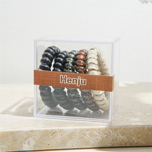 Detail view of neutral earth-toned spiral hair ties in a clear square gift box
