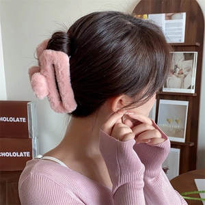 Dettaglio di un grande fermaglio per capelli in ecopelliccia rosa indossato da una modella