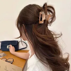 Detailed view of an amber marble acetate hair claw clip on long hair with a matte finish