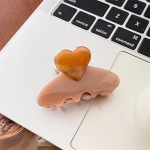 Nahaufnahme der herzförmigen Haarklammer aus Acetat in Rosa auf einem Laptop