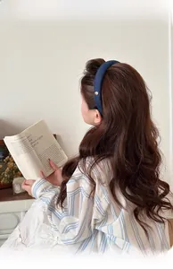 Détail d'un serre-tête rembourré en denim bleu marine avec un bouton doré vintage chic