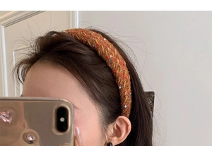 Close-up of a tweed headband with colorful fiber accents on a woven brown fabric