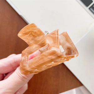 Detail view of rectangular amber marble hair claw clip with glossy acetate finish