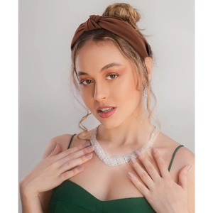 Close-up of a wide knot headband and sparkling rhinestone necklace on a model