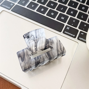Detailed close-up of marble pattern acetate hair claw clip with black and white ink texture