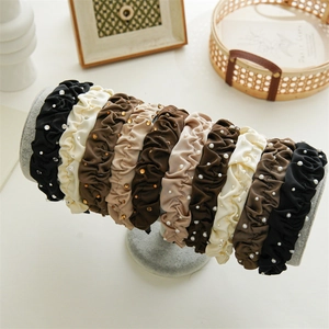 Detailed view of satin pleated headbands with faux pearls and rhinestones on display