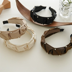 Detail of four pleated satin headbands with pearl accents in black, khaki, white, and brown