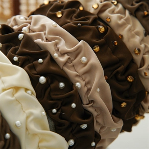 Detailed macro view of pleated satin headband with pearls and sparkling rhinestones
