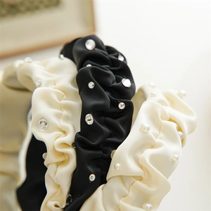 Detail view of satin pleated headbands decorated with shimmering pearls and rhinestones