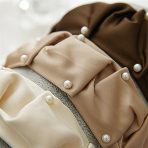 Close-up of pleated satin headbands with artificial pearls in ivory, khaki, and dark coffee