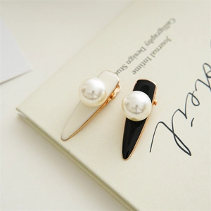 Detail of elegant pearl hair clips in black and white with glossy finish and gold trim