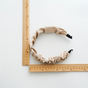 Champagne pleated satin headband with pearls, showing dimensions with wooden rulers