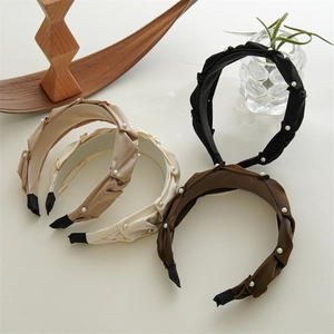 Detail of four pleated fabric headbands with white pearls in black, brown and beige colors