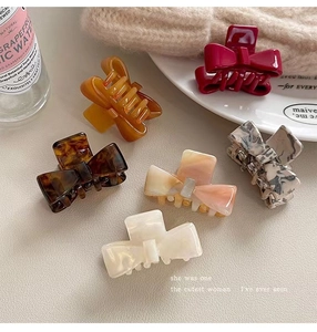 Flat lay of 6 assorted acetate bow hair claws in tortoiseshell and marble patterns