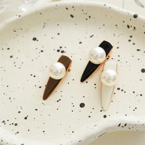 Three elegant pearl hair clips in brown, black, and cream displayed on ceramic tray