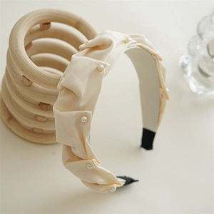 Detail of elegant pleated cream fabric headband with delicate white pearl embellishments