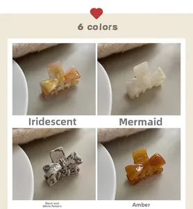 Detail of four small acetate bow hair claws in marble, amber, and iridescent finishes
