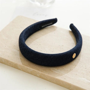 Détail d'un serre-tête en denim bleu avec bouton doré sur pierre de marbre